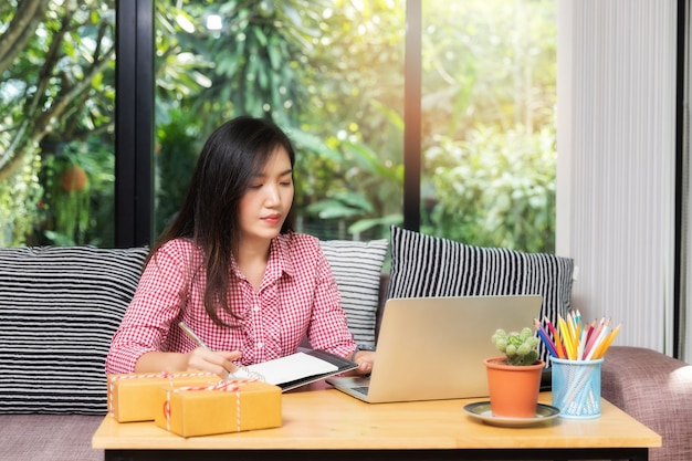 Mujer de negocios con ventas online y envío de paquetería en su oficina en casa