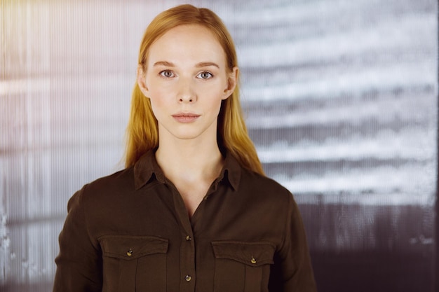 Mujer de negocios vestida casual adulta amistosa que se coloca derecha. Concepto de una foto de negocios o retrato en la oficina.