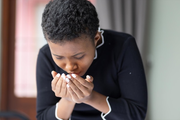 Mujer negra africana enferma estornudando y con secreción nasal concepto de brote de virus de la gripe alérgica enfermedad de atención médica que propaga el control de brotes