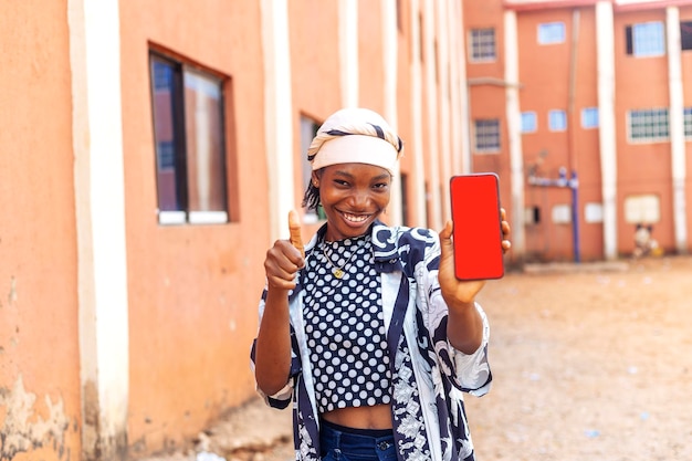 Foto mujer negra africana feliz sosteniendo el teléfono levanta el pulgar para el concepto de aprobación