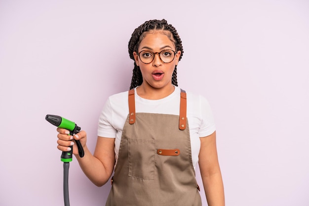 Mujer negra afro que parece muy conmocionada o sorprendida. concepto de manguera de jardinero