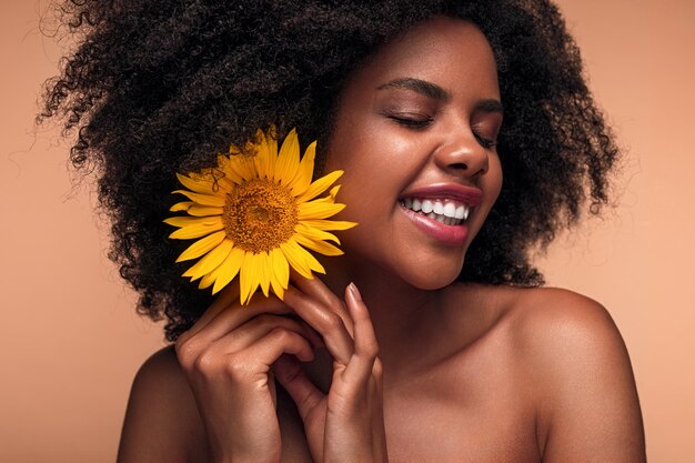 Mujer negra alegre decorando el cabello con girasol