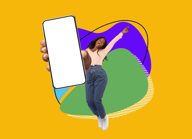 Una mujer negra alegre saltando con un gran smartphone en blanco sobre un fondo colorido abstracto
