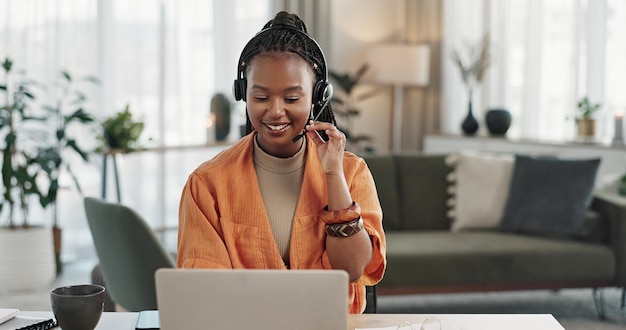 Mujer negra auriculares en la oficina de casa con portátil y llamada telefónica trabajo remoto y crm en el apartamento Asistente virtual en el escritorio con computadora escribiendo y conversando para asesoramiento chat en línea y soporte