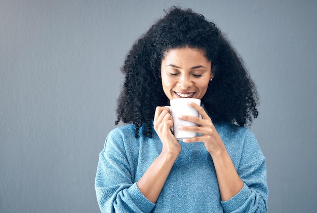 Mujer negra bebe y café en el fondo del estudio y el telón de fondo de la maqueta Sonrisa feliz de la joven modelo africana con una taza de té capuchino y una taza de café con leche para romper la felicidad y burlarse de la bebida