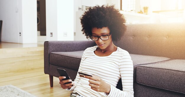 Mujer negra casa y relajarse con tarjeta de crédito o teléfono inteligente para el pago de compras digitales y compras en línea para transacciones seguras Girl piso y banca móvil para suscripción y tienda virtual