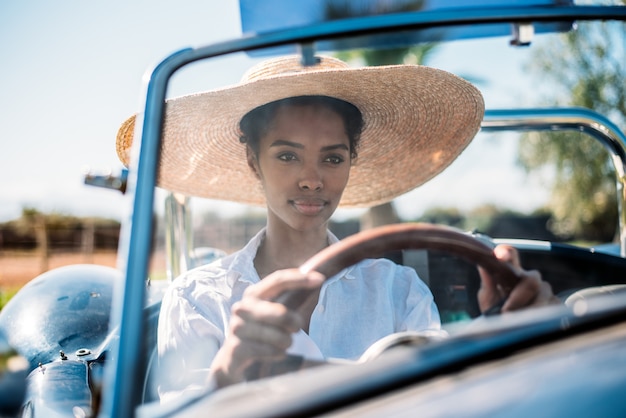 Mujer negra conduciendo un coche descapotable vintage