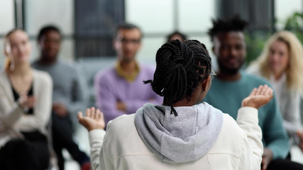 Mujer negra dando una conferencia de negocios a jóvenes empresarios sentados en sillas