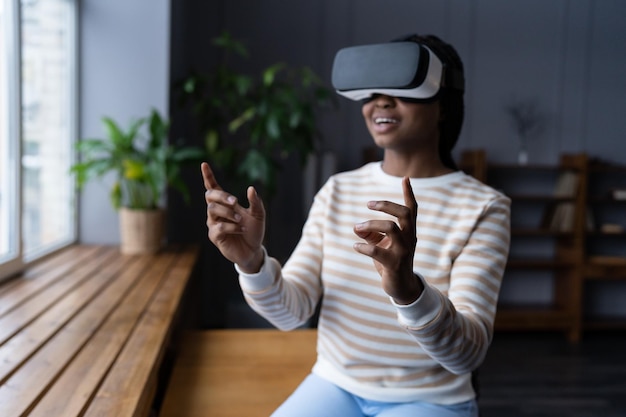 Una mujer negra emocionada usa gafas de auriculares vr juega un videojuego de realidad virtual con gafas sola en casa