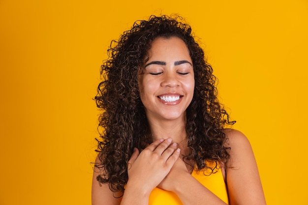 mujer negra feliz agradecida esperanzada cogida de la mano en el pecho sintiéndose agradecida agradecida, sincera dama africana expresando amor sincero apreciación gratitud honestidad