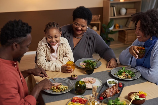 Una mujer negra feliz disfrutando de la cena con su familia.