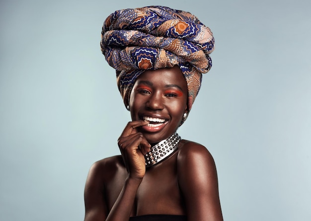 Mujer negra feliz con moda de turbante africano y belleza con maquillaje aislado en el fondo del estudio Sonrisa de cosmética natural en retrato y modelo femenino con envoltura de cabeza tradicional juguetona y con estilo