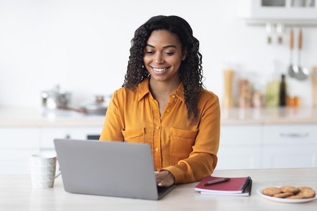 Mujer negra feliz trabajando desde casa escribiendo en el cuaderno