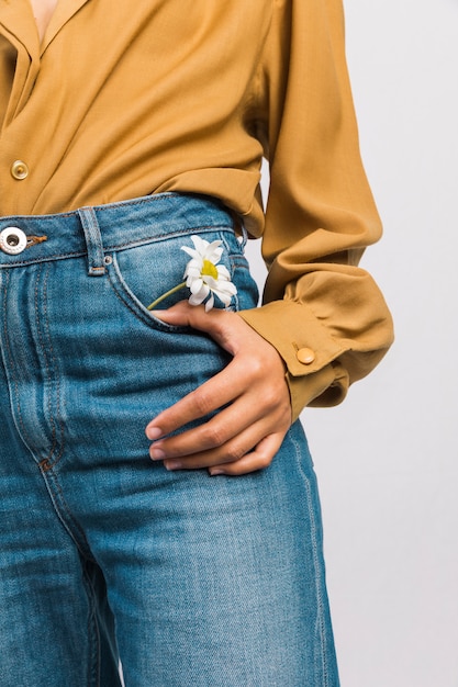 Mujer negra con flor de margarita en bolsillo de jeans