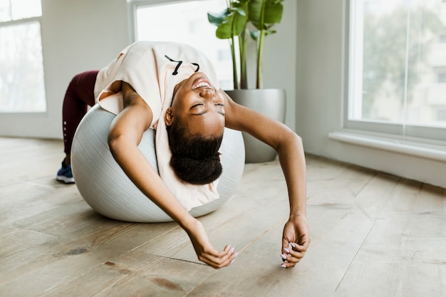 Mujer negra haciendo estiramientos en una bola de equilibrio