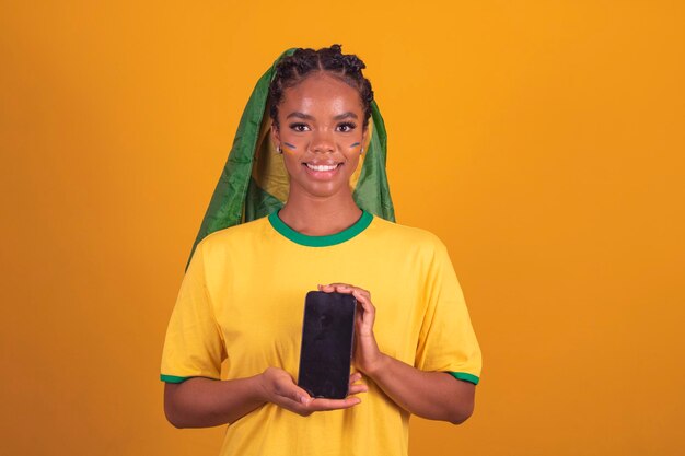 Mujer negra joven aficionado al fútbol brasileño con aplicación de teléfono móvil uso móvil de teléfono inteligente