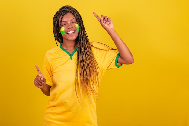 Foto mujer negra joven aficionado al fútbol brasileño haciendo un baile de celebración