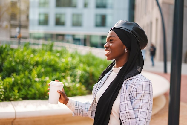 Mujer negra musulmana feliz bebiendo café y riendo