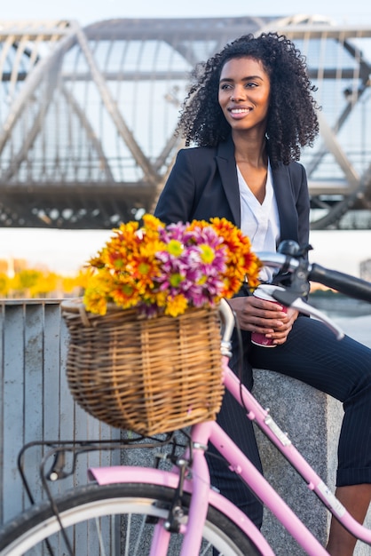 Mujer negra de negocios con bicicleta vintage bebiendo café