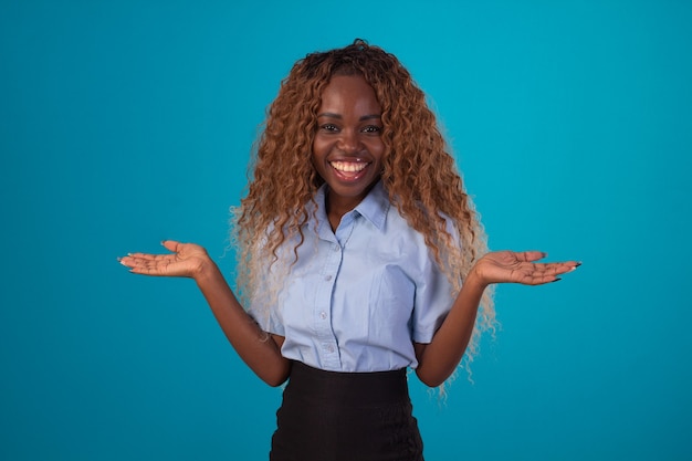 Mujer negra con pelo rizado en foto de estudio con camisa azul y falda negra y haciendo varias expresiones faciales.