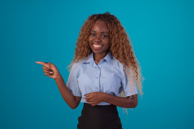 Mujer negra con pelo rizado en foto de estudio con camisa azul y falda negra y haciendo varias expresiones faciales.