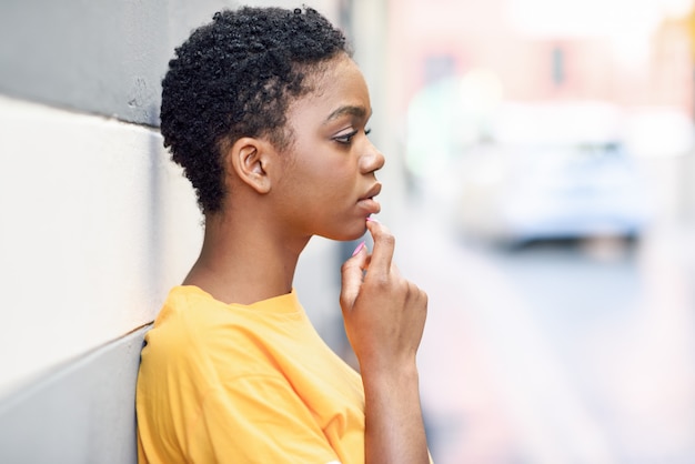 Mujer negra pensativa con expresión triste al aire libre.