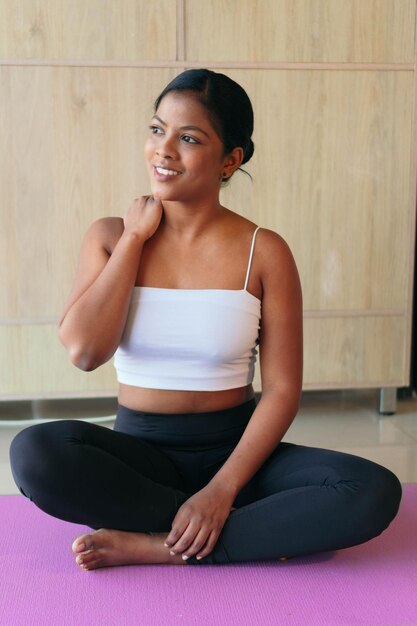 Mujer negra practicando yoga, haciendo ejercicio, vistiendo ropa deportiva, pantalón negro y top.