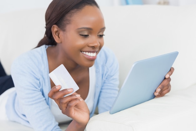 Mujer negra que miente en el frente que sostiene una tarjeta de crédito