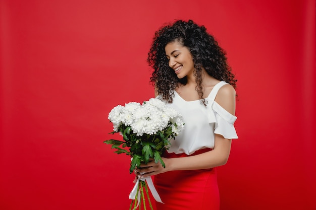 Mujer negra con ramo de flores blancas con falda aislada en rojo