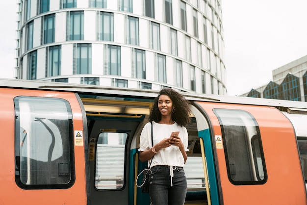 Foto mujer negra con teléfono móvil en el metro de londres