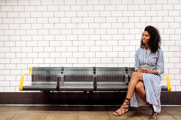 Mujer negra con teléfono móvil en el metro de Londres