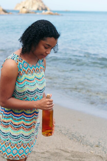 Mujer negra, tenencia, un, botella de vino, en la playa