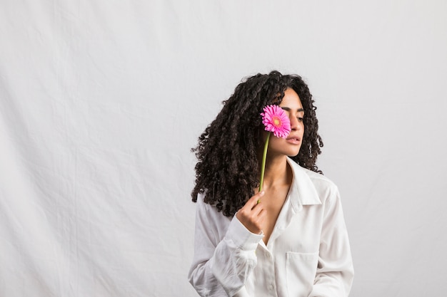 Foto mujer negra, tenencia, gerbera, en, cara