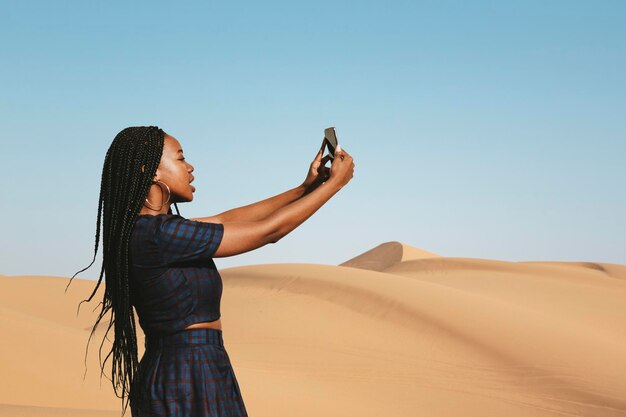 Mujer negra tomando una foto en un desierto