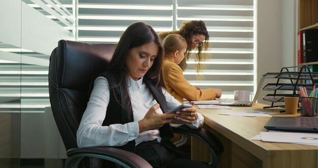 Mujer nerviosa hablando por teléfono estando en la oficina con dos compañeros de trabajo