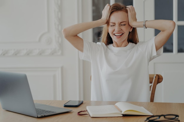 Mujer nerviosa sentada en la computadora portátil sostenga la cabeza preocupada por el error Fracaso personal estrés en el trabajo