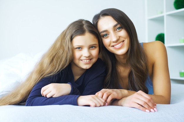 Mujer y niña acostada en la cama sonriendo