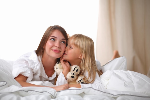 Mujer y niña acostada en la cama sonriendo