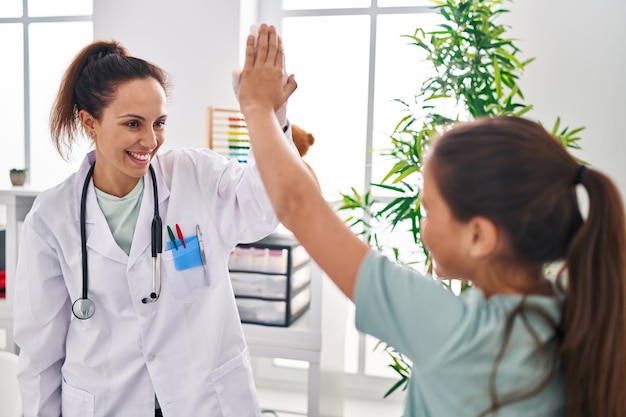 Mujer y niña doctora y paciente chocan los cinco con las manos levantadas en la clínica