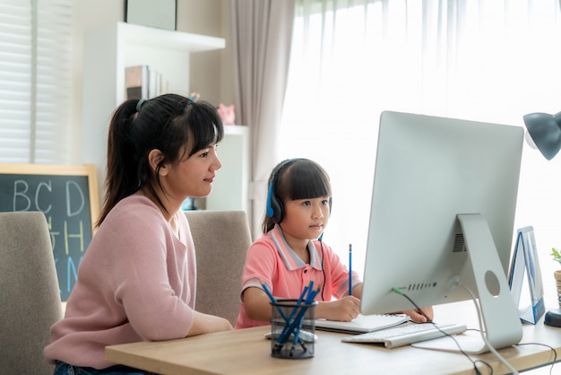 Mujer con una niña frente a una computadora