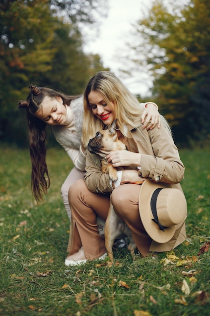 Mujer, niña y perro jugando en el parque de otoño