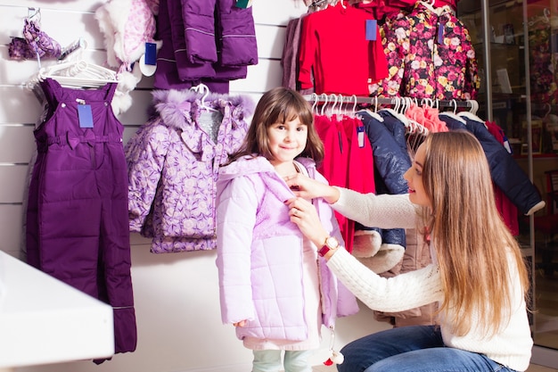 La mujer y la niña se pusieron una chaqueta rosada en una tienda de ropa
