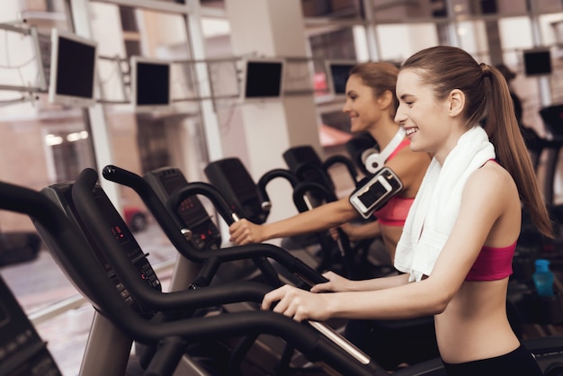 Mujer y niña en ropa deportiva corriendo en cinta en el gimnasio