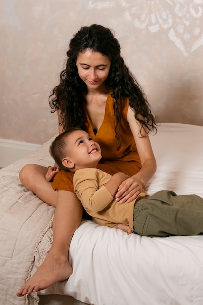 Mujer y niño en la cama tiro completo