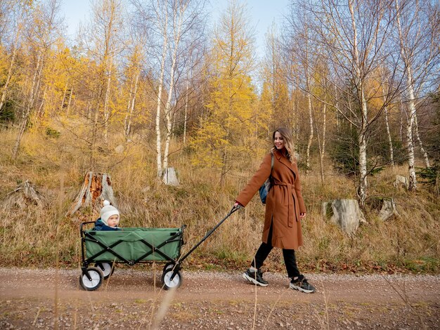 Mujer con un niño en un carro caminando por el bosque