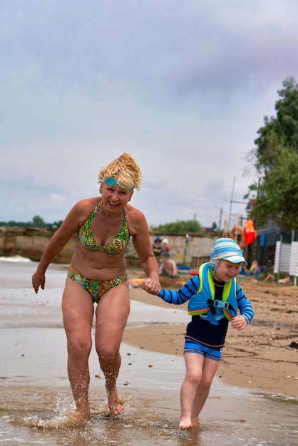 Una mujer y un niño están caminando por el mar tomados de la mano.