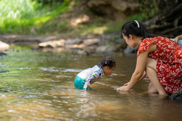 Una mujer y un niño están parados en el agua y uno de ellos lleva un traje de baño rojo y blanco.