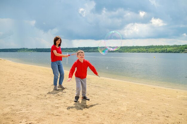 Una mujer y un niño jugando con burbujas en la playa.