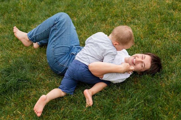 Foto mujer y niño jugando en pasto full shot