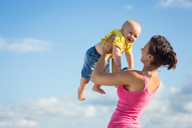 Una mujer con un niño jugando en la playa, mamá con bebé en la naturaleza